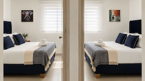 A mirrored view of a hotel room with two beds, a window with blinds, and artwork on the walls. - Tropical Midnight | Sunset Views & Pool, Wi-Fi (Cartagena)