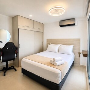 Ein Hotelzimmer mit Bett, Schreibtisch, Stuhl, Kleiderschrank und Deckenleuchte.