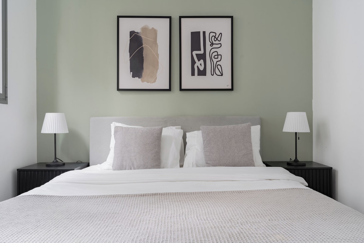 A neatly made bed with a textured white cover, two bedside lamps, and a headboard.