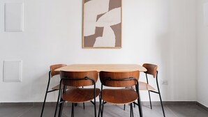 A dining area with a wooden table and four chairs, a framed abstract artwork on the wall, and a whiteboard on the left. - Blueground - Historical Preserved Estate (Tel Aviv-Yafo)