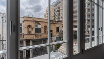 Vista a través de una ventana de un edificio con varios balcones y una calle abajo.