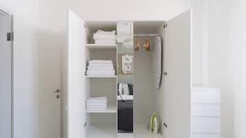 Un vestidor amplio y blanco con estantes para toallas dobladas y espacio para colgar ropa.