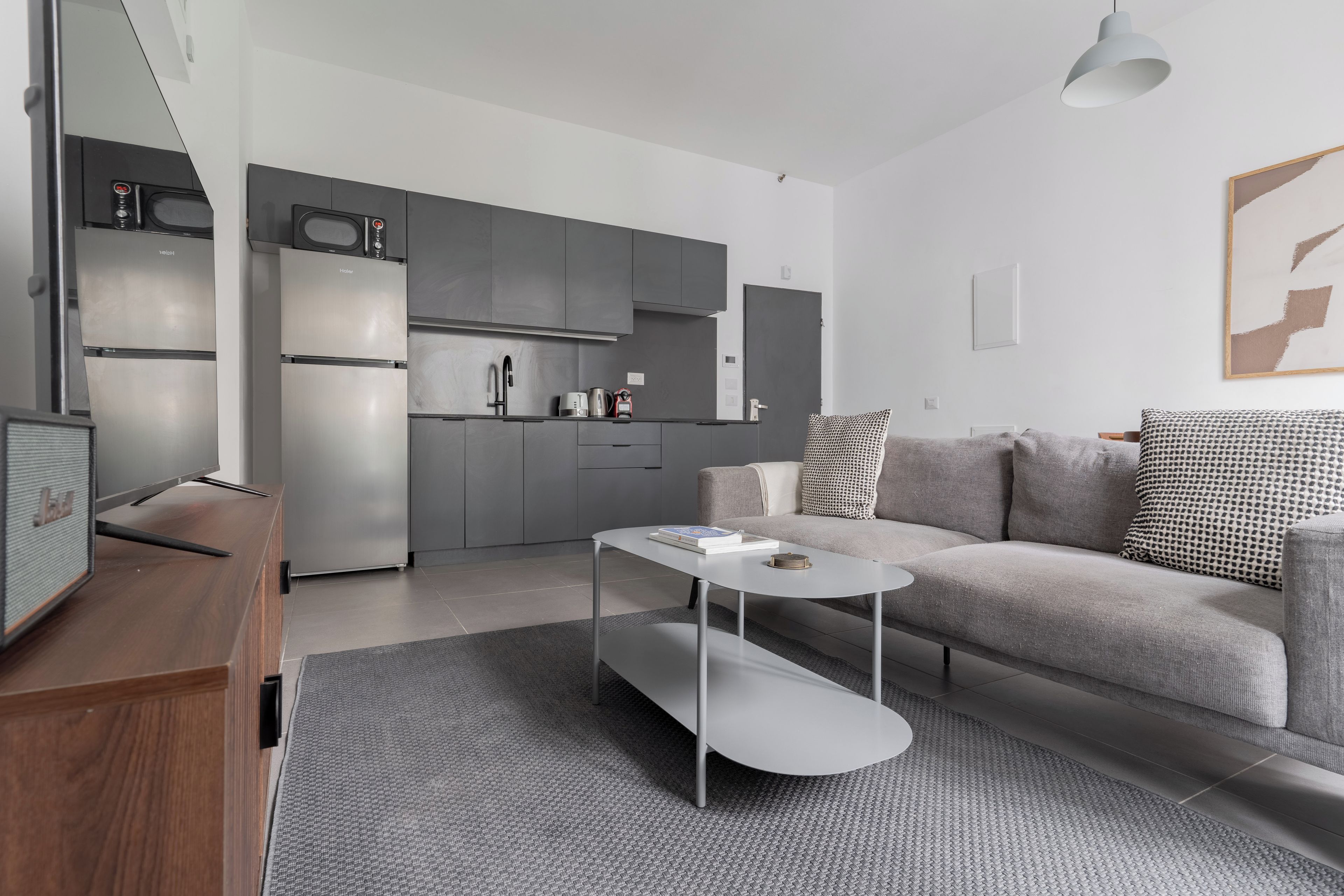 Una sala de estar moderna con un sofá gris, una mesa de centro y un televisor de pantalla plana.