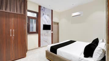 A bedroom with a bed, a wardrobe, a television, and an air conditioning unit.
