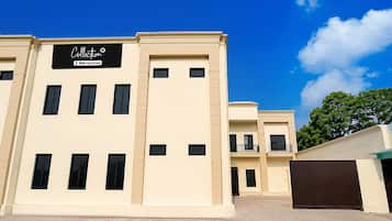 A multi-story building with a beige facade, a sign reading 'Collection OYO-Serviced', and a gated entrance.