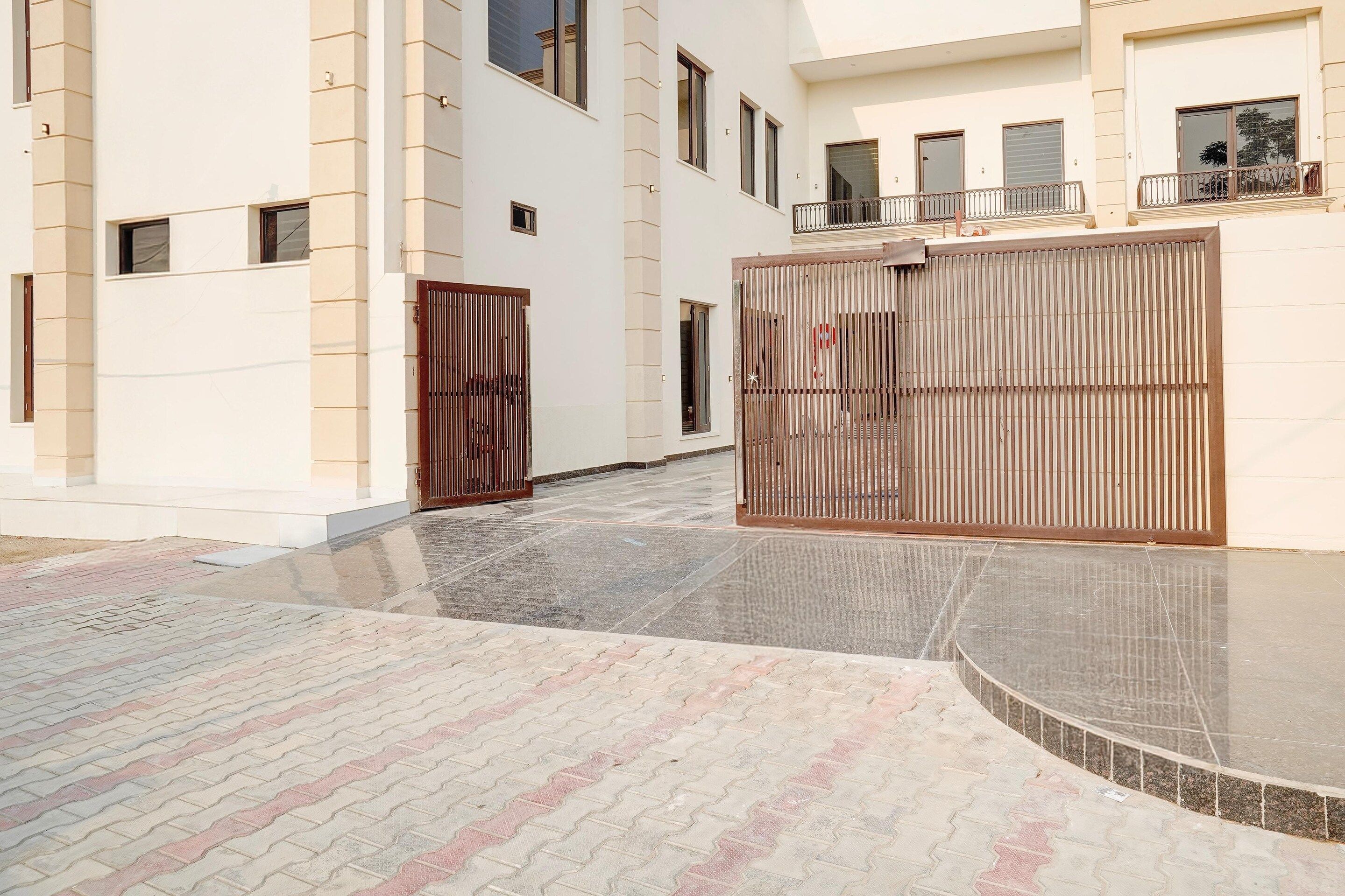 A gated entrance to a building with a tiled pathway leading to the entrance.