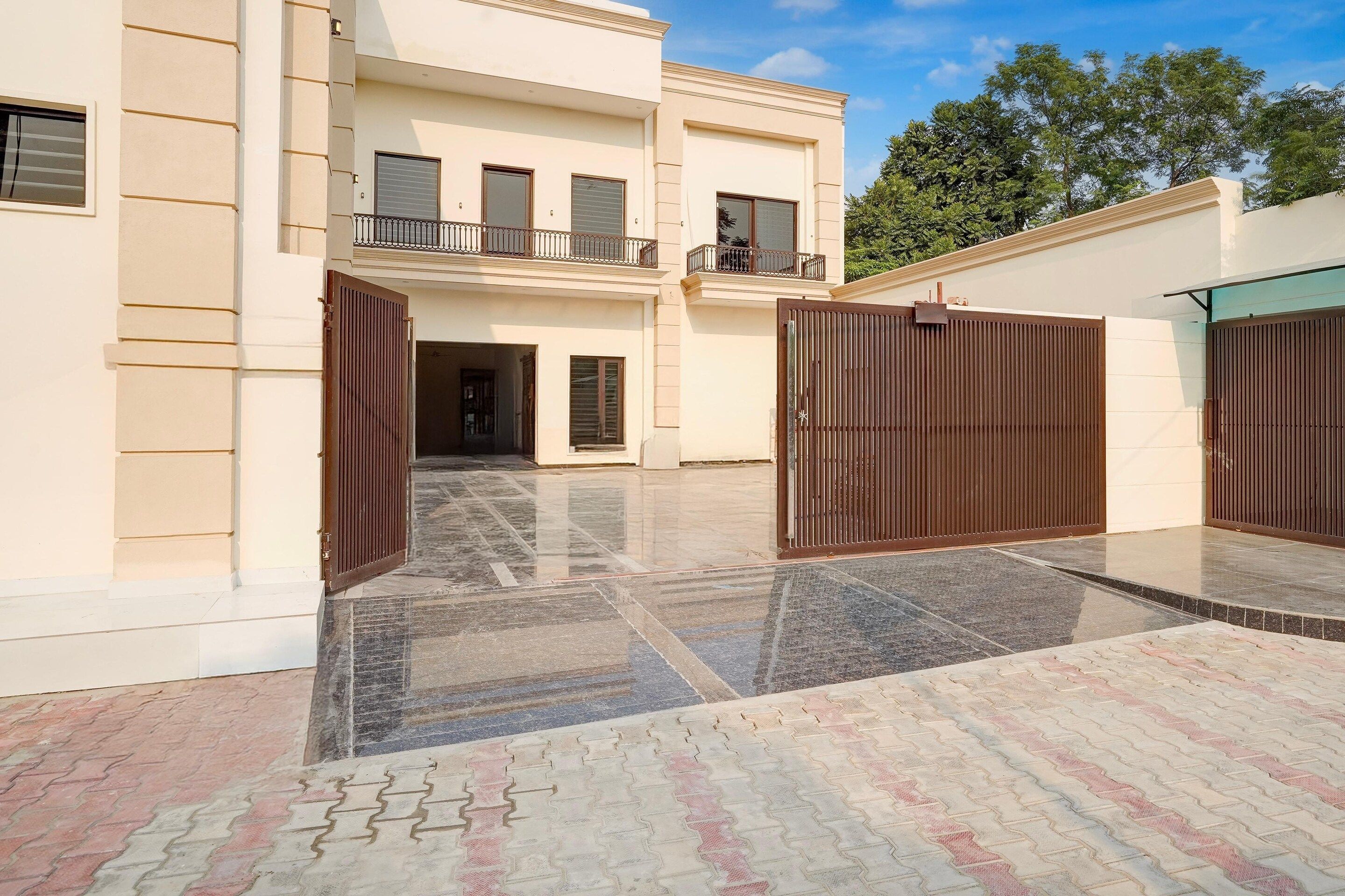 A multi-story building with a gated entrance, a balcony, and a tiled courtyard.