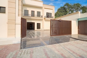 A multi-story building with a gated entrance, a balcony, and a tiled courtyard.