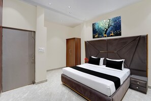 Una habitación de hotel con una cama grande, un armario, una mesita de noche y un cuadro en la pared.