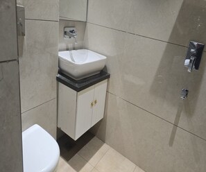 A bathroom with a white sink, a toilet, and a cabinet with a mirror. - Collection O City Centre Sapror (Phagwara)