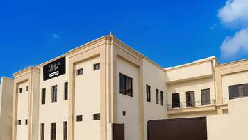 A modern building with a flat facade, multiple windows, and a prominent sign on the front.