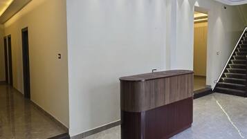 Un interior moderno con una recepción, una escalera y un pasillo con puertas.