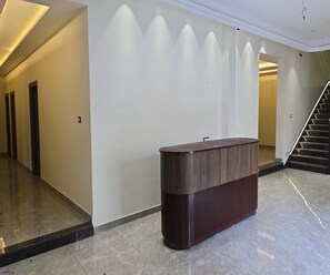 A modern interior with a reception desk, a staircase, and a hallway with doors. - Collection O City Centre Sapror (Phagwara)