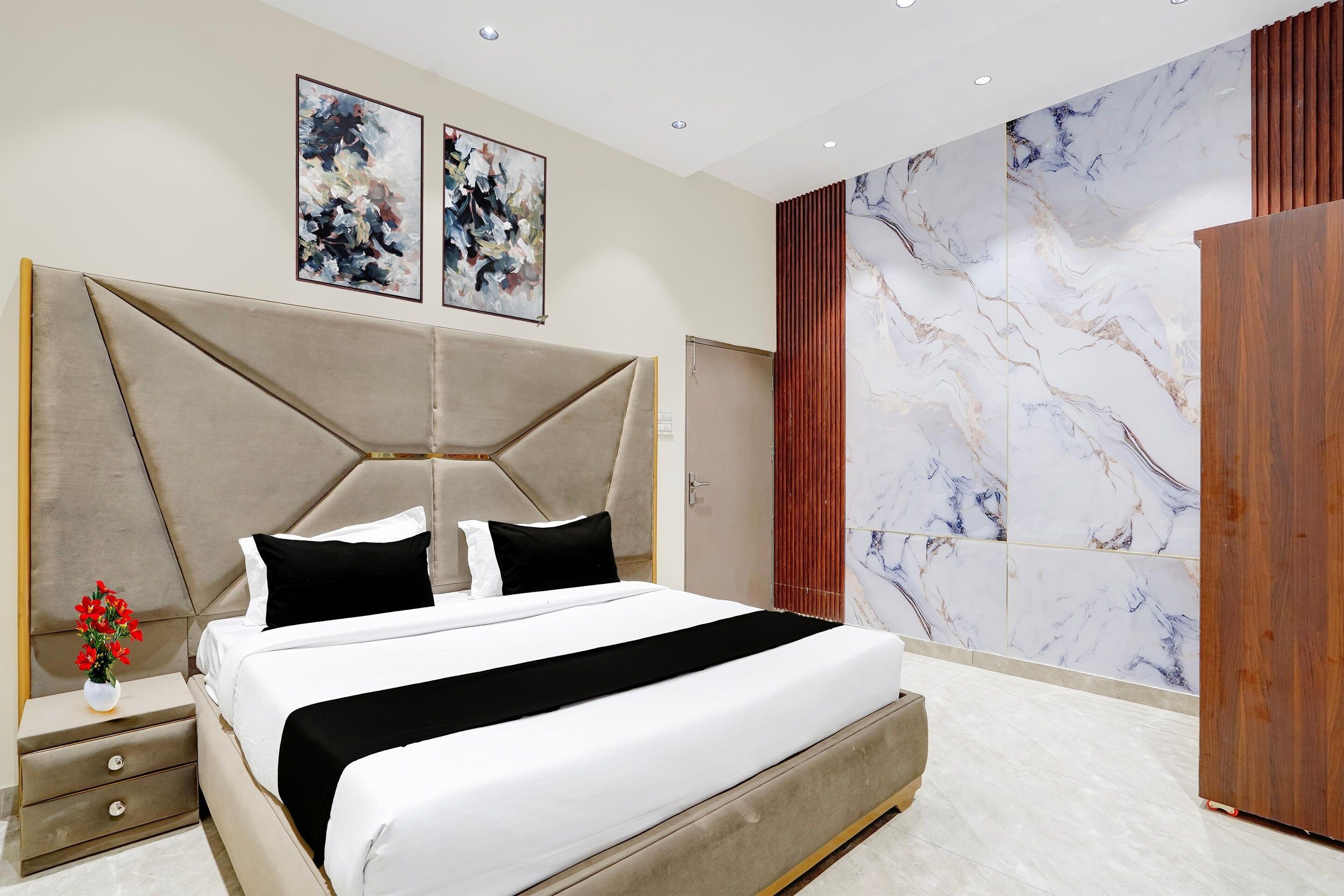 A modern bedroom with a large bed, a nightstand, a wooden wardrobe, and abstract art on the wall.