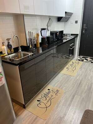 A modern kitchen with stainless steel appliances, a black countertop, and a patterned backsplash. - Inaya Haven Kileleshwa (Nairobi)
