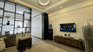 Una sala moderna con sofá, una mesa de centro, televisor y dispensador de agua.