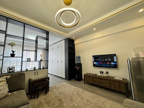 Una sala moderna con sofá, una mesa de centro, televisor y dispensador de agua.