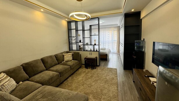 Una sala moderna con un sofá modular, un televisor de pantalla plana y un mueble empotrado para entretenimiento.
