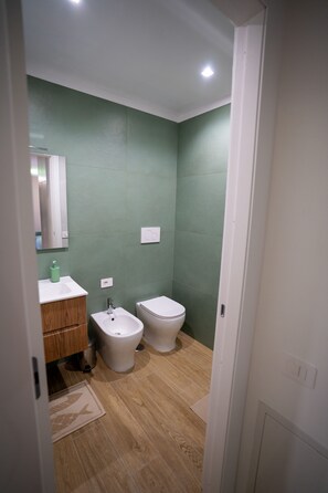 A bathroom with a wooden floor, a white sink, a bidet, and a toilet. - Brezza di Mare - Sea, Passion, Relax (Terracina)