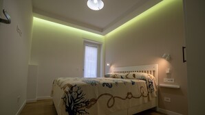 Ein Schlafzimmer mit einem Bett, einem Fenster und einer Wandleuchte.