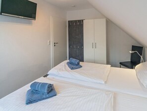 Ein Hotelzimmer mit Bett, Schreibtisch, Stuhl, Kleiderschrank und Fernseher.