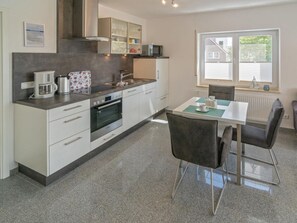 Eine moderne Küche mit Einbauofen, Mikrowelle und Kaffeemaschine. Es gibt einen Essbereich mit Tisch und Stühlen.