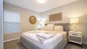 A bedroom with a bed, bedside tables, a window with blinds, and a wall decoration. - Prime Location 4BR Le Reve with Pool Near Disney (Kissimmee)