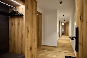 A hallway with wooden walls and floors, a black door handle, and a hanging coat rack. - Modern Suite With Outdoor Sauna (Gaschurn)