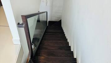 Una escalera con escalones de madera oscura y barandilla de vidrio.