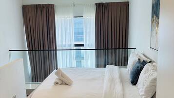 Ein Hotelzimmer mit Bett, Nachttisch, Vorhängen und Blick auf die Stadt.