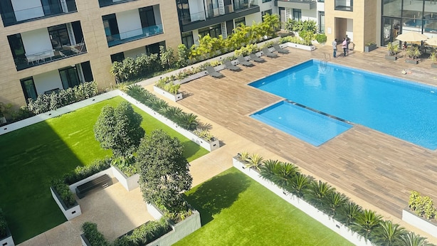 A modern building with a swimming pool, multiple balconies, and a well-maintained lawn. - Phil's Properties At Embassy Gardens GH (Accra)