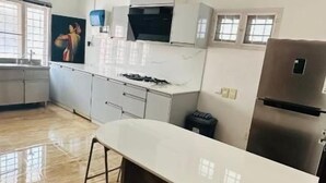A modern kitchen with a white countertop, stainless steel appliances, and a ceiling fan. - Cleety's by MGDC (Kochi)