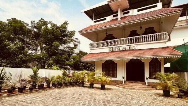 A multi-story building with a courtyard, balconies, and potted plants. - Cleety's by MGDC (Kochi)