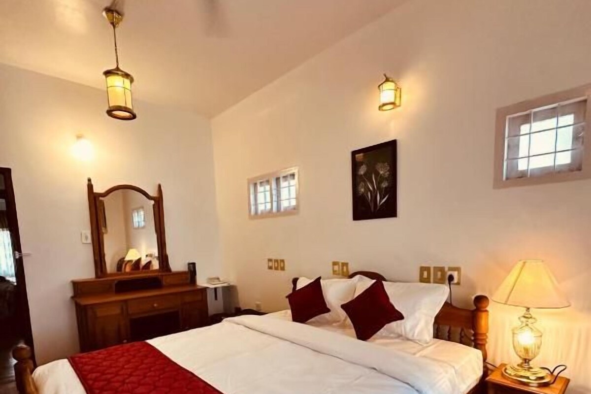 Ein Schlafzimmer mit einem hölzernen Bett, einem Nachttisch mit Lampe, einem Deckenventilator und einem Fenster mit Jalousien.