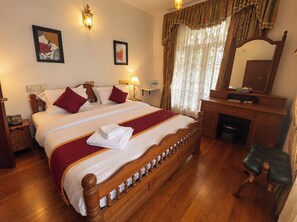 Ein Hotelzimmer mit einem großen Bett, einem Holz-Kopfteil, einem Schreibtisch mit Spiegel und einem Stuhl.