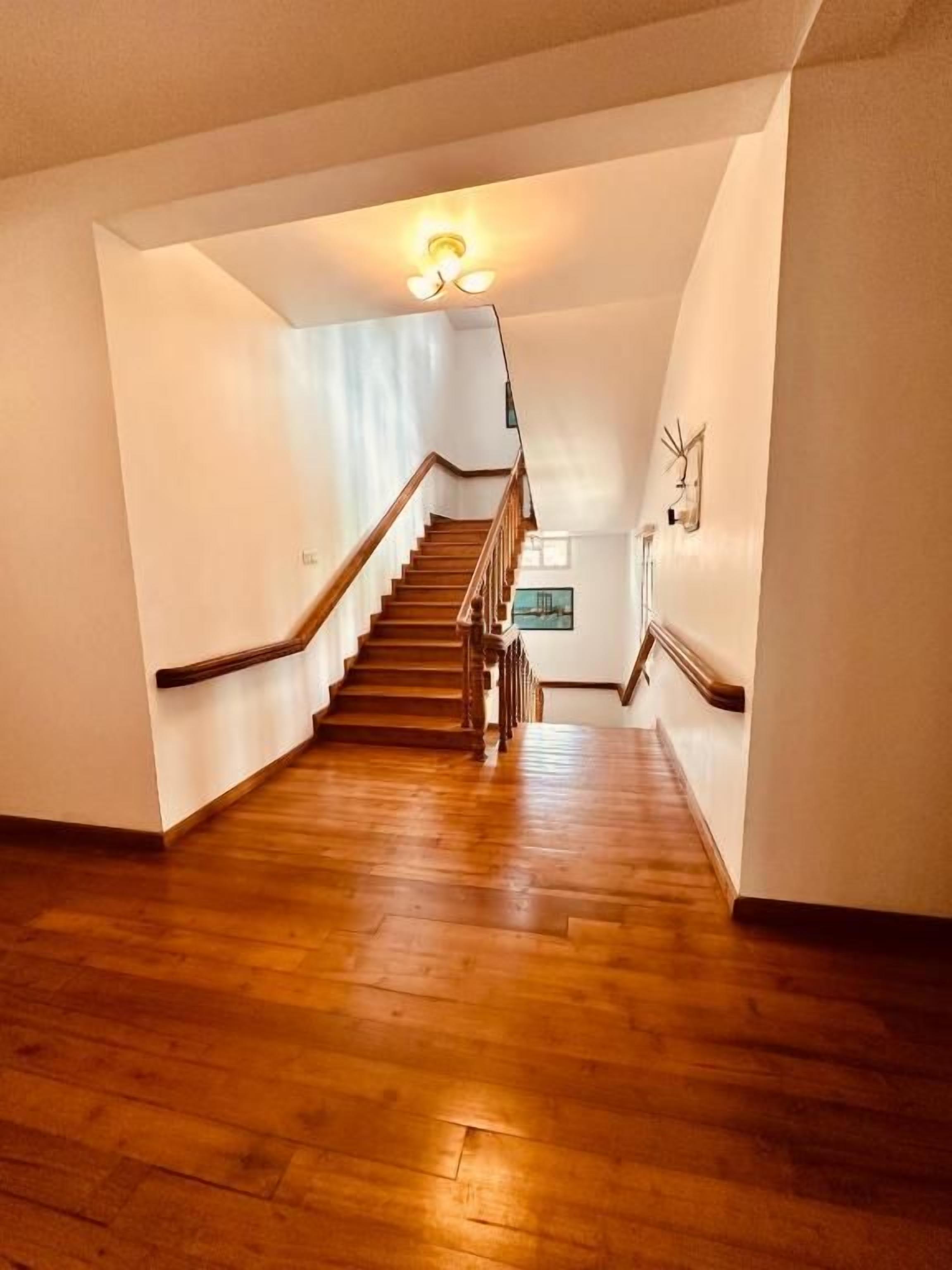 A staircase with wooden steps and a handrail, leading to a landing with a light fixture.