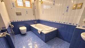 A bathroom with a bathtub, toilet, and shower. - Cleety's by MGDC (Kochi)