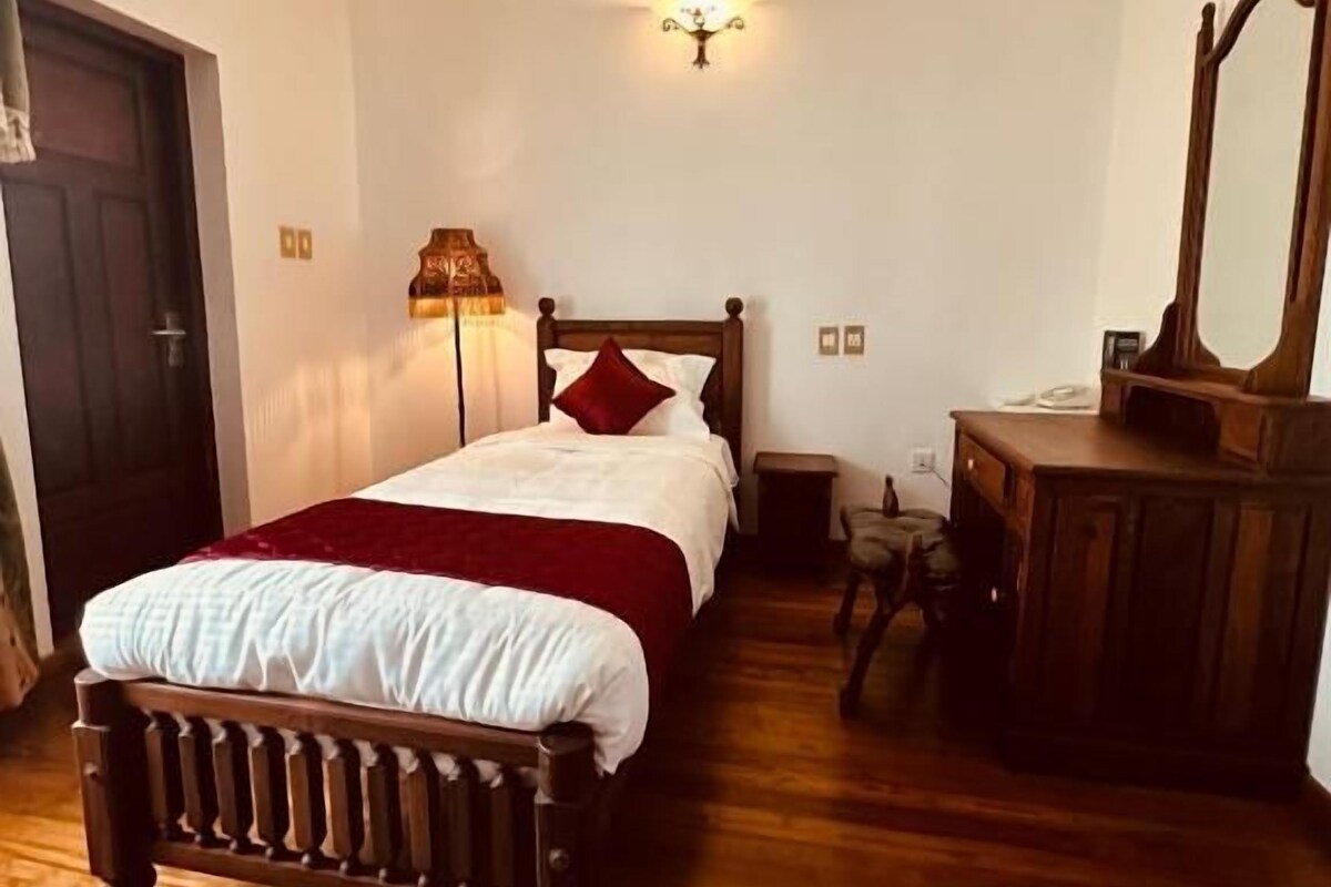 Ein Schlafzimmer mit einem hölzernen Bett, einem Nachttisch, einem Spiegel und einer Lampe.