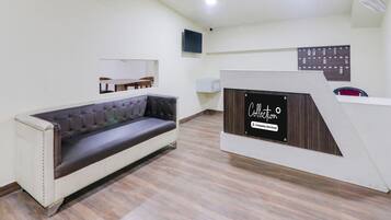 A modern interior with a sofa, a reception desk, and a mounted television.