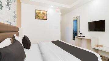 A hotel room with a bed, a desk, a mirror, and a television.