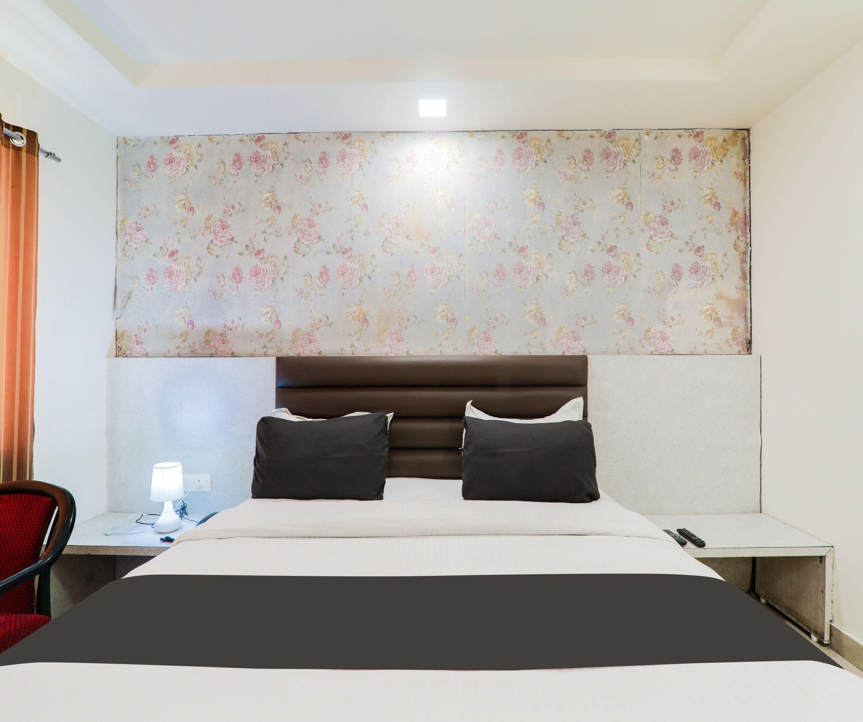 A hotel room with a bed, a bedside table, a lamp, and a chair.