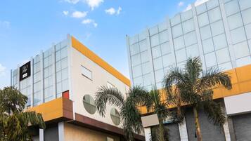 A modern building with large windows and a flat roof, surrounded by palm trees.