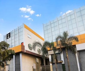Un edificio moderno con grandes ventanales y techo plano, rodeado de palmeras.
