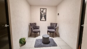 Une petite pièce avec deux chaises, une table ronde et un tableau encadré accroché au mur.