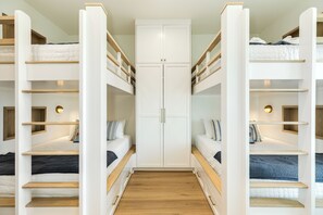 A room with bunk beds, a wardrobe, and a small window. - Getaway to 7 Saturdays - Beachside! Beautiful New Construction 2nd Row Home (Galveston)