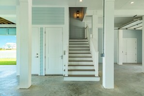 A staircase leading to a landing with a light fixture above, surrounded by white walls and doors. - Getaway to 7 Saturdays - Beachside! Beautiful New Construction 2nd Row Home (Galveston)