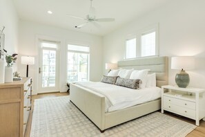 Een slaapkamer met een bed, nachtkastjes, een ventilator aan het plafond en een raam.