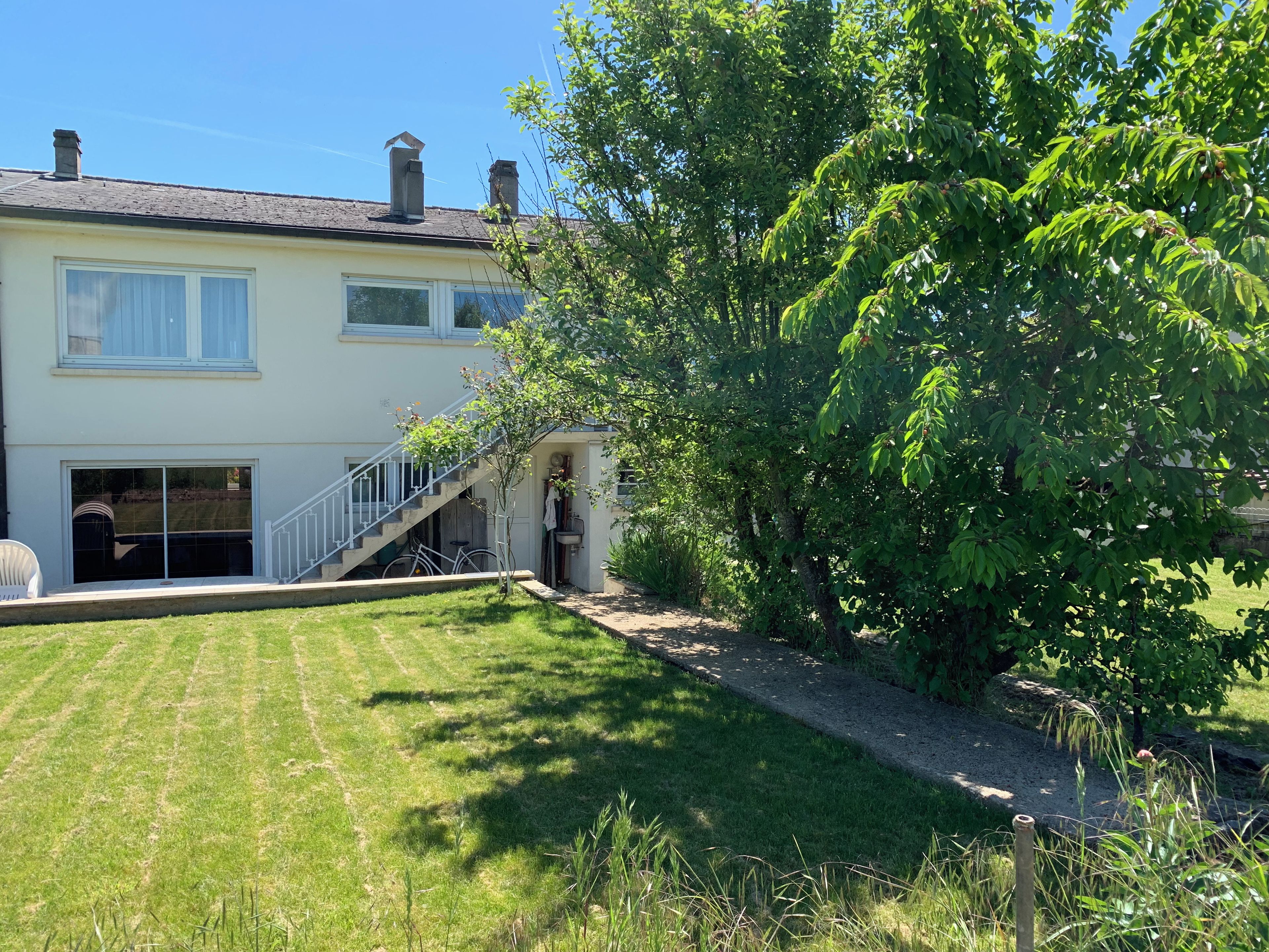 A two-story house with a visible staircase leading to the upper floor, a garage door, and a well-maintained lawn.