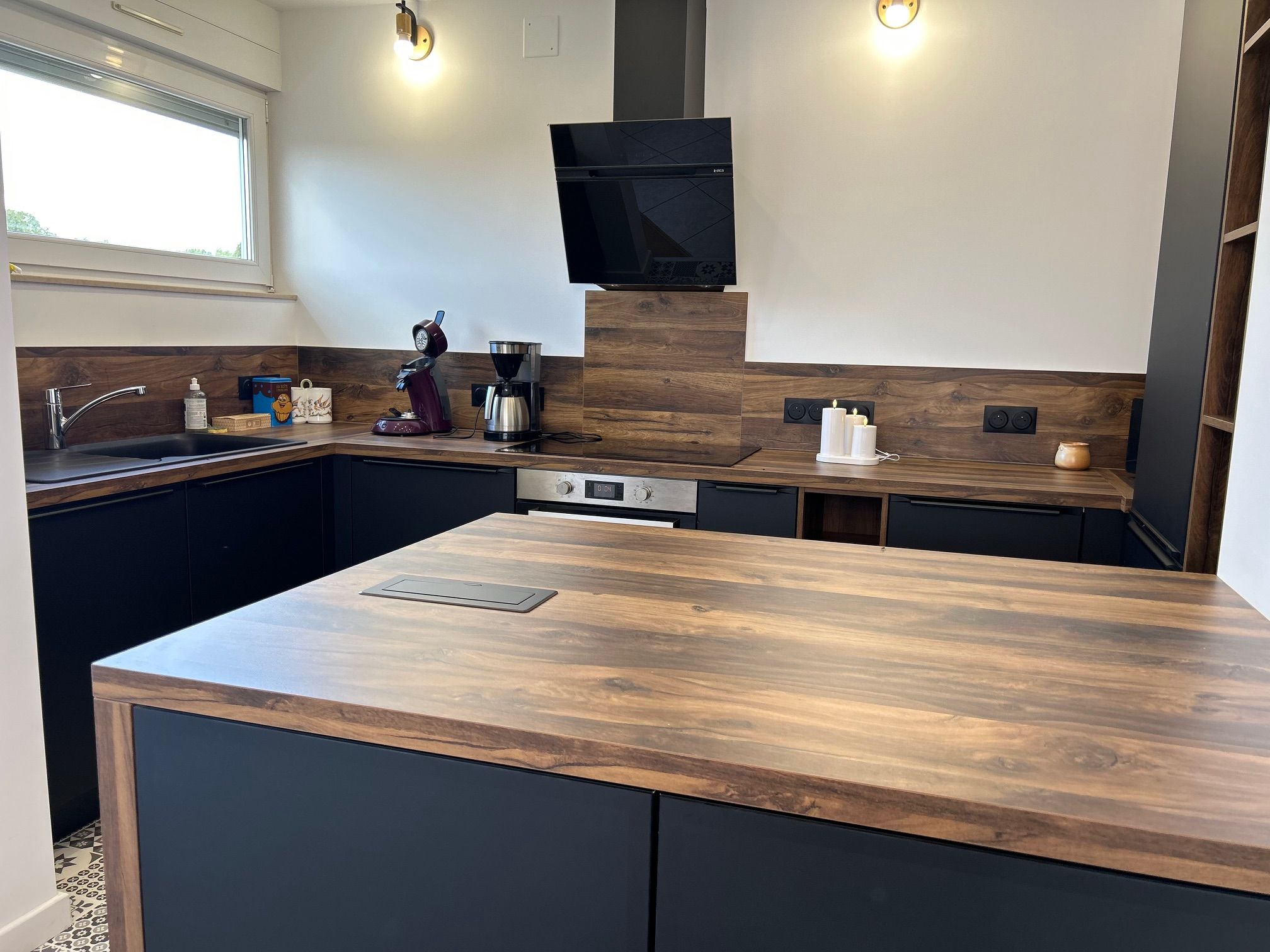 Une cuisine moderne dotée d’un îlot central, d’appareils électroménagers intégrés et d’une grande fenêtre.