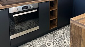 Cuina moderna amb forn integrat, microones i taulell de fusta.